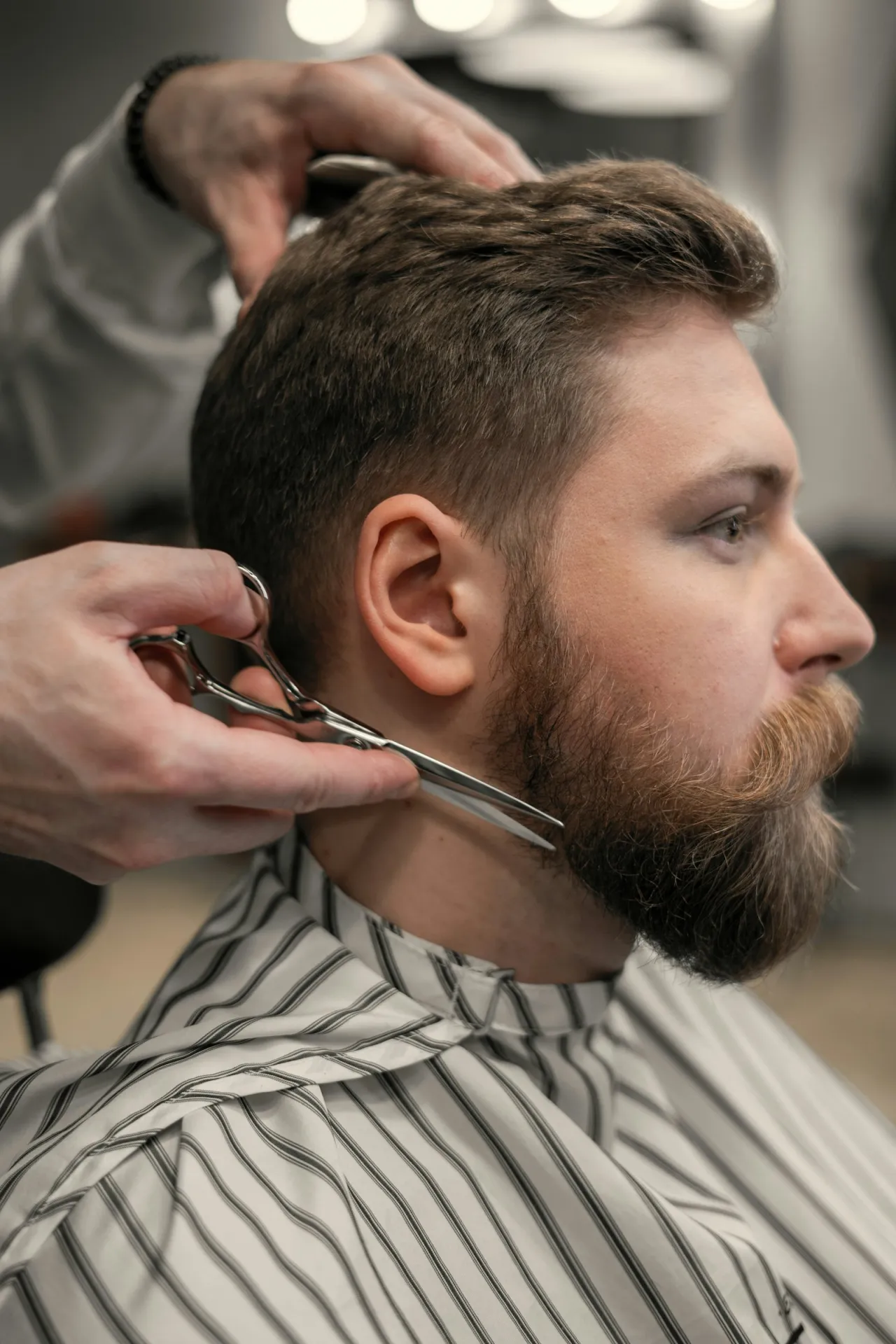 Barbero recortando la barba de un cliente con tijera