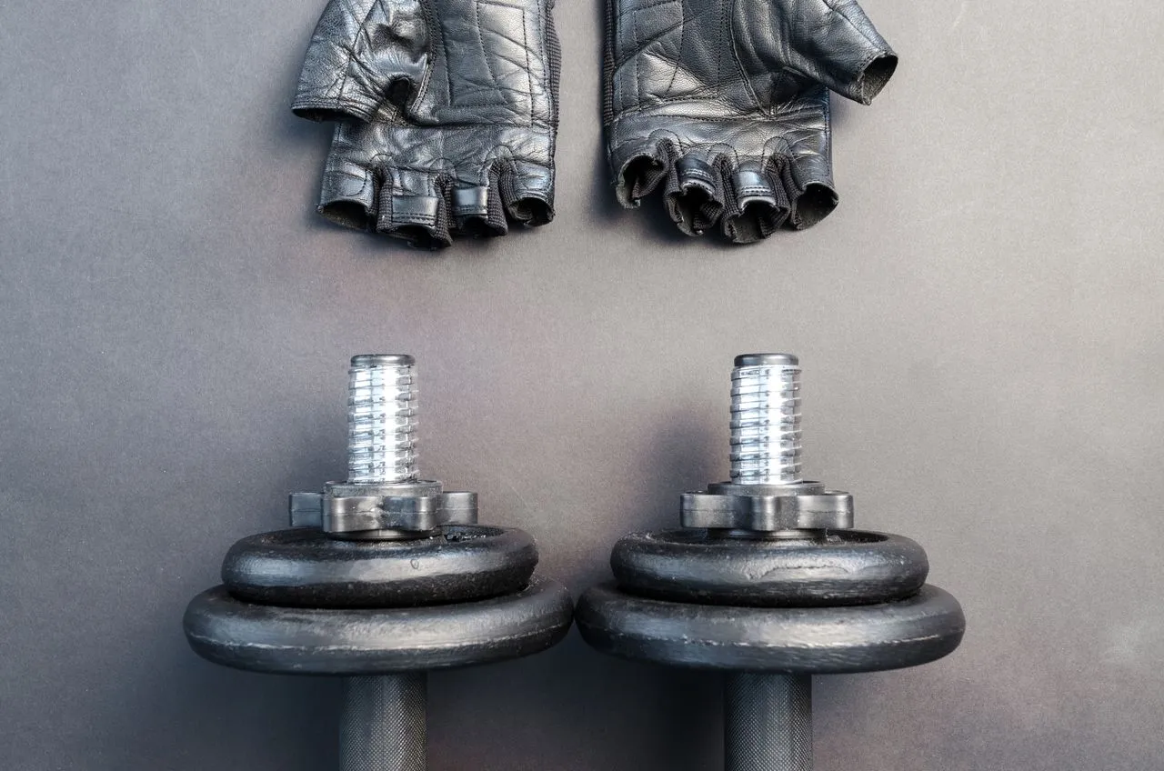 Guantes de entrenamiento junto a dos mancuernas